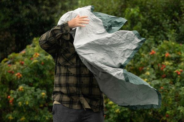 A tourist struggled with a rain po<em></em>ncho that is wrapped around him by the wind.