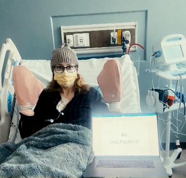 Jenna Fischer in a hospital bed with a laptop, after sharing her breast cancer treatment journey