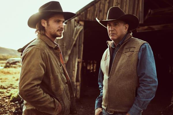 Luke Grimes standing with Kevin Costner. 