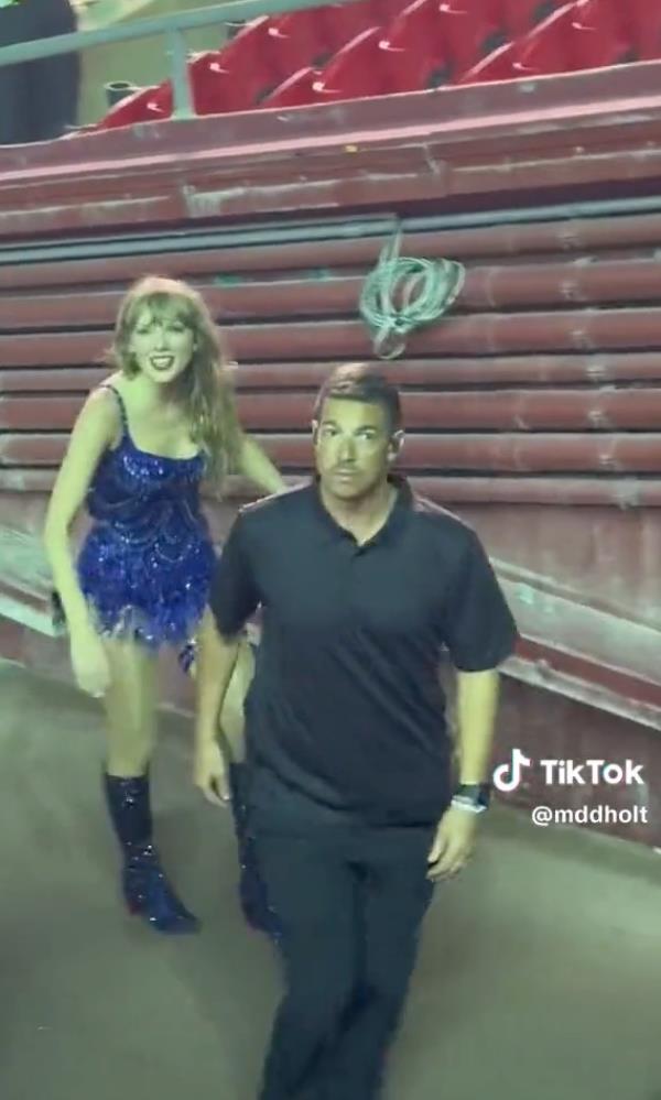 Taylor Swift in a sparkly blue dress and her body guard during the Eras tour. 