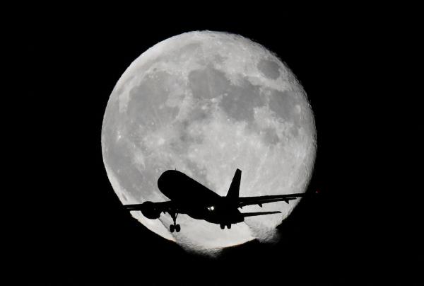 Aircraft passes in front of moon near Heathrow Airport in London