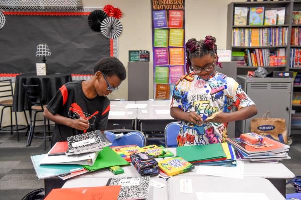 Gabriel Cook and Avery Dodson sorting and labeling their school supplies at a table during the first day of class at University Place Elementary