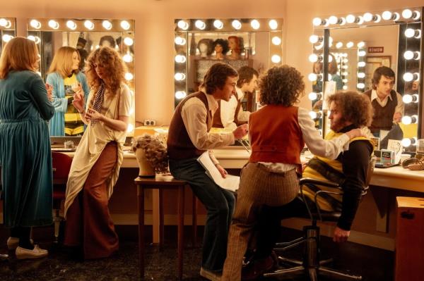 An image of people in 70s clothes in a dressing room getting ready 