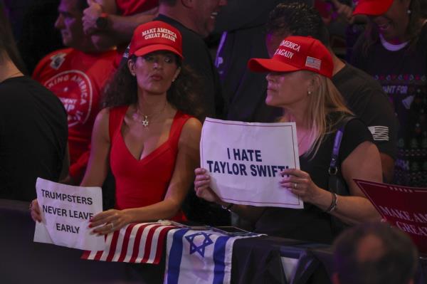 People in the crowd hold signs a<em></em>bout Taylor Swift and rally goers leaving early before former US President and Republican nominee for President Do<em></em>nald Trump arrives to a rally at the Nassau Veterans Memorial Coliseum in Unio<em></em>ndale, New York, USA, 18 September 2024.