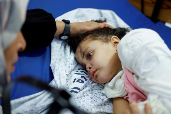 Palestinian girl Fulla Al-Laham, 4, who was wounded in an Israeli strike that killed 14 family members, including her parents and all her siblings, lies on a bed as her grandmother sits next to her, at a hospital in Khan Younis in the southern Gaza Strip, October 14, 2023. REUTERS/Mohammed Salem