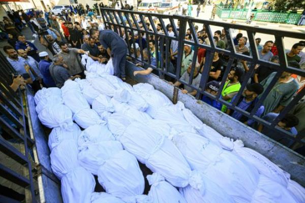 A lorry carries bodies wrapped in burial shrouds of the Abu al-Awf family, displaced from northern Gaza and killed in a home housing internally displaced Palestinians, as they are taken for burial from the Al-Aqsa hospital in the town of Deir Al-Balah, in the central Gaza Strip, on October 15, 2023. Israeli forces were on October 15, readying for a looming Gaza ground invasion aimed at destroying Hamas, the Palestinian Islamist militant group that unleashed the bloodiest attack in the country's history. (Photo by Mahmud HAMS / AFP) (Photo by MAHMUD HAMS/AFP via Getty Images)