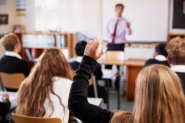 Children in a school classroom with hand raised