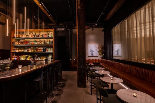 Interior view of Kinjo, an omakase restaurant in DUMBO, featuring a long bar table with chairs and custom sake.