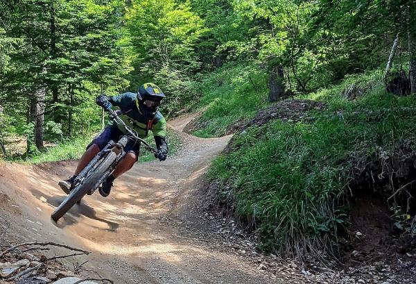 Person riding mountain bike on dirt path in a wooded area