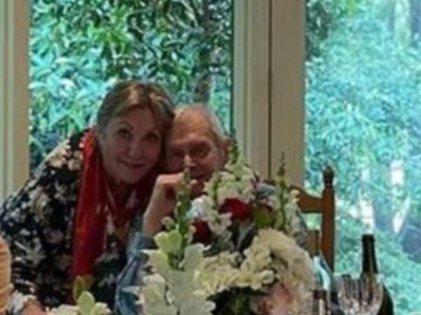 Jillian and John Farnham embrace at the head of the table.