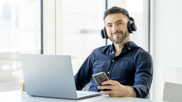 man listening to music with headpho<em></em>nes while holding phone