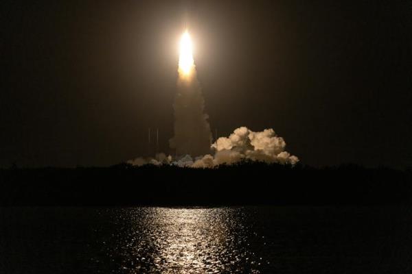 A rocket launching into the air over water at nighttime