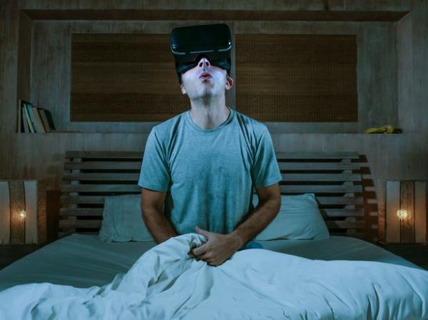 young excited and aroused man at home wearing 3d virtual realty goggles havin<em></em>g fun on bed playing alone with internet cyber sex VR simulator masturbating in sexual illusion and desire