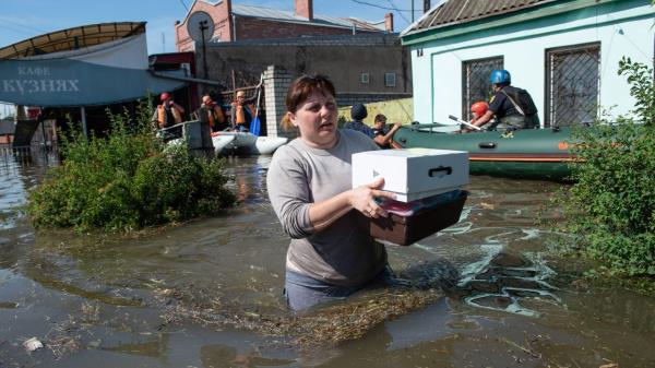 A woman wades through waist-high water after retrieving some belo<em></em>ngings from her home in Kherson after the bursting of the Kakhovka dam. 