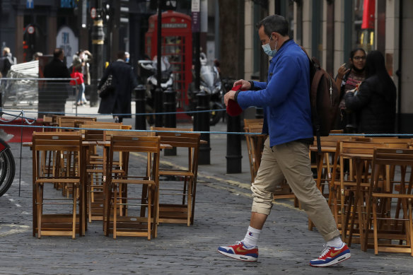 A man walks past empty tables of a restaurant in London. The UK has still not bounced back from the pandemic.